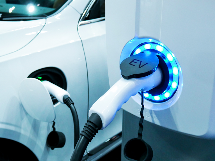 A photograph of an electric vehicle plugged into a charging station.